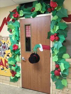 a door decorated with green and red paper poinsettis, holly leaves and a black hat