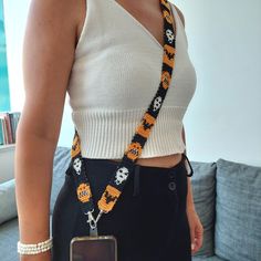 a woman wearing a halloween themed lanyard with a cell phone in her hand and a camera strap around her neck