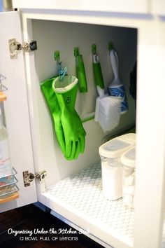 green gloves hanging from hooks in a cabinet