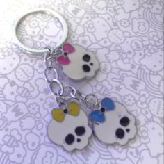 two key chains with skulls and bows on them are sitting on a white tablecloth