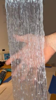 a person holding up some plastic wrap on top of a table