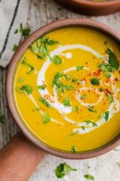 two bowls filled with soup and garnished with parsley on the rims