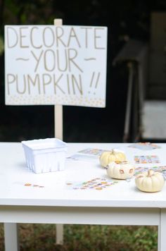 a table with pumpkins and a sign that says decorate your pumpkin