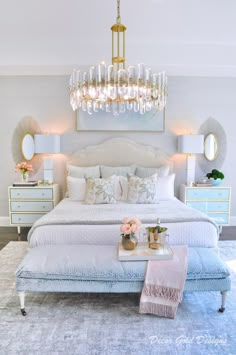 a bedroom with a large bed, chandelier and two nightstands on either side