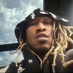 a man with dreadlocks on his head sitting in a car looking at the camera