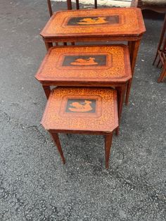 three wooden tables sitting next to each other on top of a cement ground with chairs in the background