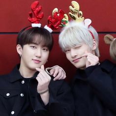 two young men wearing reindeer antlers on their heads, one is holding a cell phone