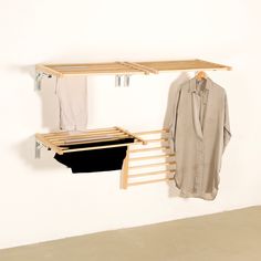 two clothes hang on wooden racks next to a white wall