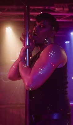 a man with his arm around a pole in the middle of a stage show,