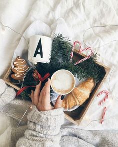 a person holding a cup of coffee in front of some cookies and candy canes