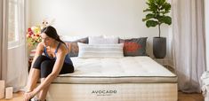 a woman sitting on top of a mattress next to a window