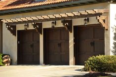 three brown garage doors in front of a house