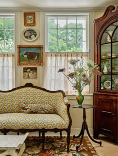 a living room filled with furniture and flowers in vases on top of a table