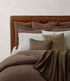 a bed with brown and white comforters, pillows and blankets on top of it