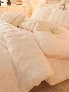 a bed with white comforters and pillows on it