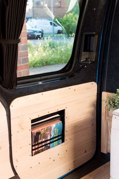 the inside of a vehicle with a magazine rack in the side door and plants growing out of it