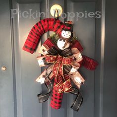 a red and black plaid christmas wreath hanging on the front door