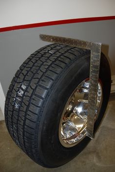 a tire with a measuring tape attached to it's side on the floor in front of a wall