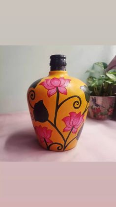 a yellow vase with pink flowers painted on it