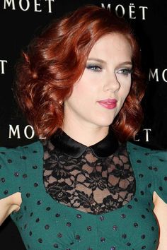 a woman with red hair wearing a green dress and black lace collared top, posing for the camera