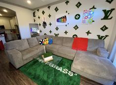 a living room filled with gray couches and green rugs on top of a hard wood floor