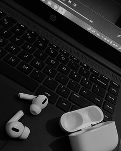 an open laptop computer sitting on top of a desk next to ear buds and headphones