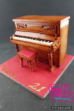 a cake shaped like a piano on top of a red sheet with a pink chair