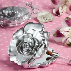 a silver rose compact mirror on a pink table