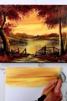 someone is painting a sunset scene on the wall with water and trees in the background