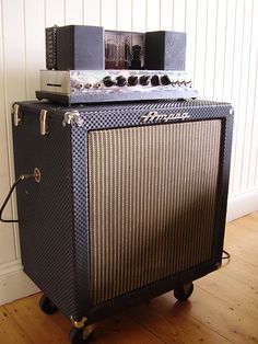 an amp sitting on top of a hard wood floor next to a wall with white paneling