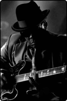 a man with a hat and guitar on stage