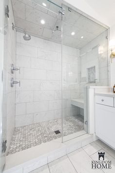 a bathroom with a walk in shower next to a white sink and counter top under lights