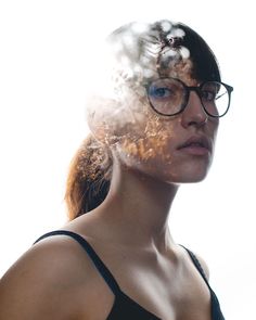 a woman with glasses is looking at the camera while she has her hair blowing in the wind