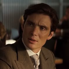 a man wearing a suit and tie in a restaurant looking at the camera with an intense look on his face