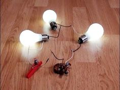 three light bulbs are connected to wires on the floor with one bulb turned upside down