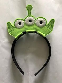 a green headband with googly eyes and a black cord around it's ears