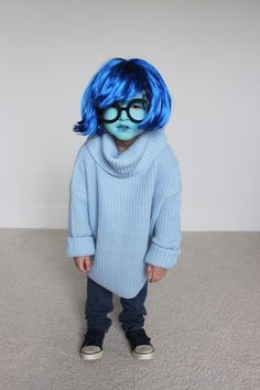 a young child with blue hair and glasses wearing a knitted sweater, jeans and sneakers