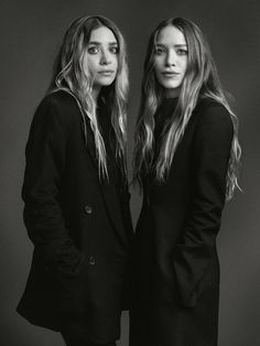 two women standing next to each other in front of a black and white photo with long hair