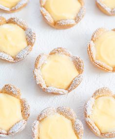 small cookies covered in powdered sugar and topped with yellow icing sit on a white surface