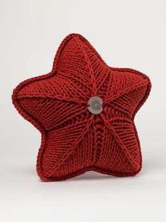 a red knitted star pillow with a button on it