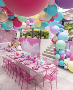 a table with pink chairs and balloons hanging from the ceiling