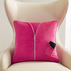 a pink pillow sitting on top of a white chair