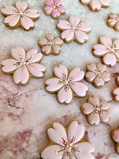 pink and gold decorated cookies sitting on top of a marble counter next to each other