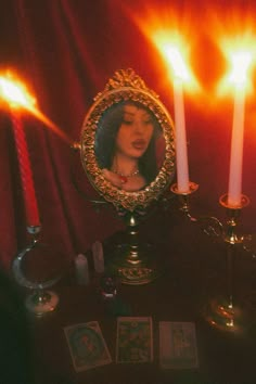 a woman looking at herself in a mirror with candles and tarot cards on the table