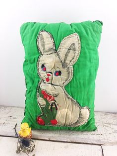 a green pillow with an image of a rabbit on it and a yellow toy next to it