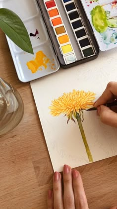 an artist's palette with watercolors and a flower