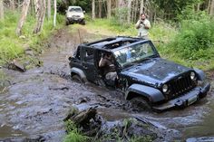 a jeep is stuck in the mud as it drives down a muddy road with two people