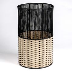 a round wicker basket with black and white stripes on the bottom, sitting in front of a white background