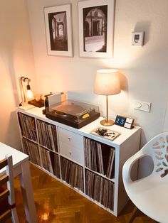 a record player sitting on top of a white shelf next to a table with a lamp