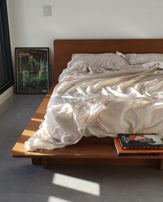 an unmade bed sitting on top of a wooden platform next to a book shelf